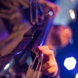 An artful photo of a person playing a black stand-up bass