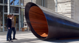 Two people stand observing an enormous, wood-lined echo tube