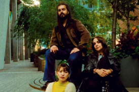 Three people pose for a photo outdoors on a fall day in the city