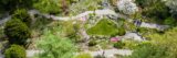 An aerial view of a green and ping garden space with rocks and two pathways going horizontally through it. Water ponds are small and in the lower right and upper middle part of the garden. There is a a group of people in one right corner and two other people walking in the middle of the lower path.