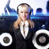 A person in a black suit and white shirt poses for a photo holding two vinyl records and wearing headphones