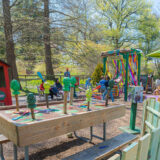 Children play in a colorful outdoor space surrounded by trees