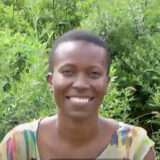 A person in a colorful blouse poses for a photo outdoors