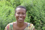 A person in a colorful blouse poses for a photo outdoors