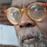 A person in brown glasses poses for a close-up photo