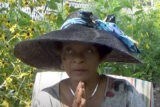 A person in a large black hat with blue ribbons poses outdoors for a photo