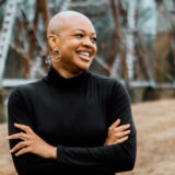 A person in a long-sleeve black shirt poses outdoors for a photo