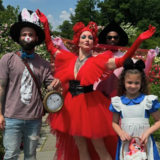 Families in costume gather for a photo with a person in a vivid red outfit