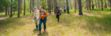 Two scientists in hiking boots lead a group through a forest, where they'll be conducting research.