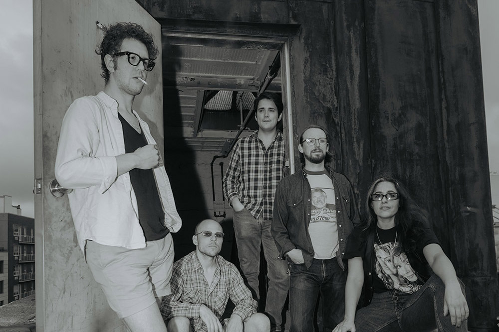 A black and white photo of a band of five people posing for the camera