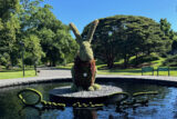 A large botanical rabbit sculpture sits in a circular pool of water with the 