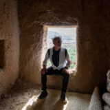 a person sits in a window of a stone building with the light shining in behind them