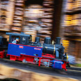 A blue and red train speeds along a model track