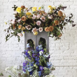 An arrangement of yellow, pink, orange, and purple flowers in a gray vase