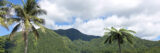 A green tropical mountain range under a blue sky