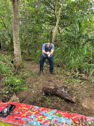 A person digs a trench in a tropical location