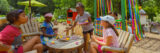 A group of children have a make-believe tea party in an outdoor play space