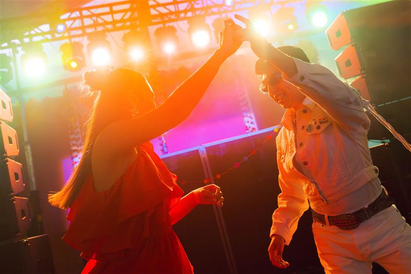 Two people dance under colorful stage lights