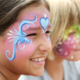 Children get their faces painted with whimsical blue and white designs