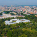 An aerial photo of a botanical garden with a city skyline in the background